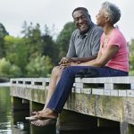 Elderly couple sitting together on a pier having freash air