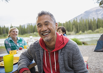 Man smiling at picnic table at campsite