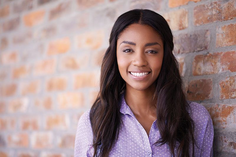 Woman standing in front of a brick wall smiling at camera