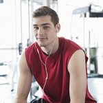 Portrait of man listening to music on smartphone at fitness center