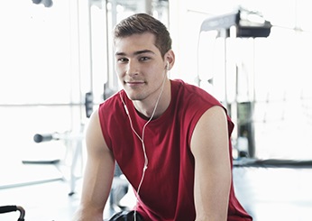 Portrait of man listening to music on smartphone at fitness center