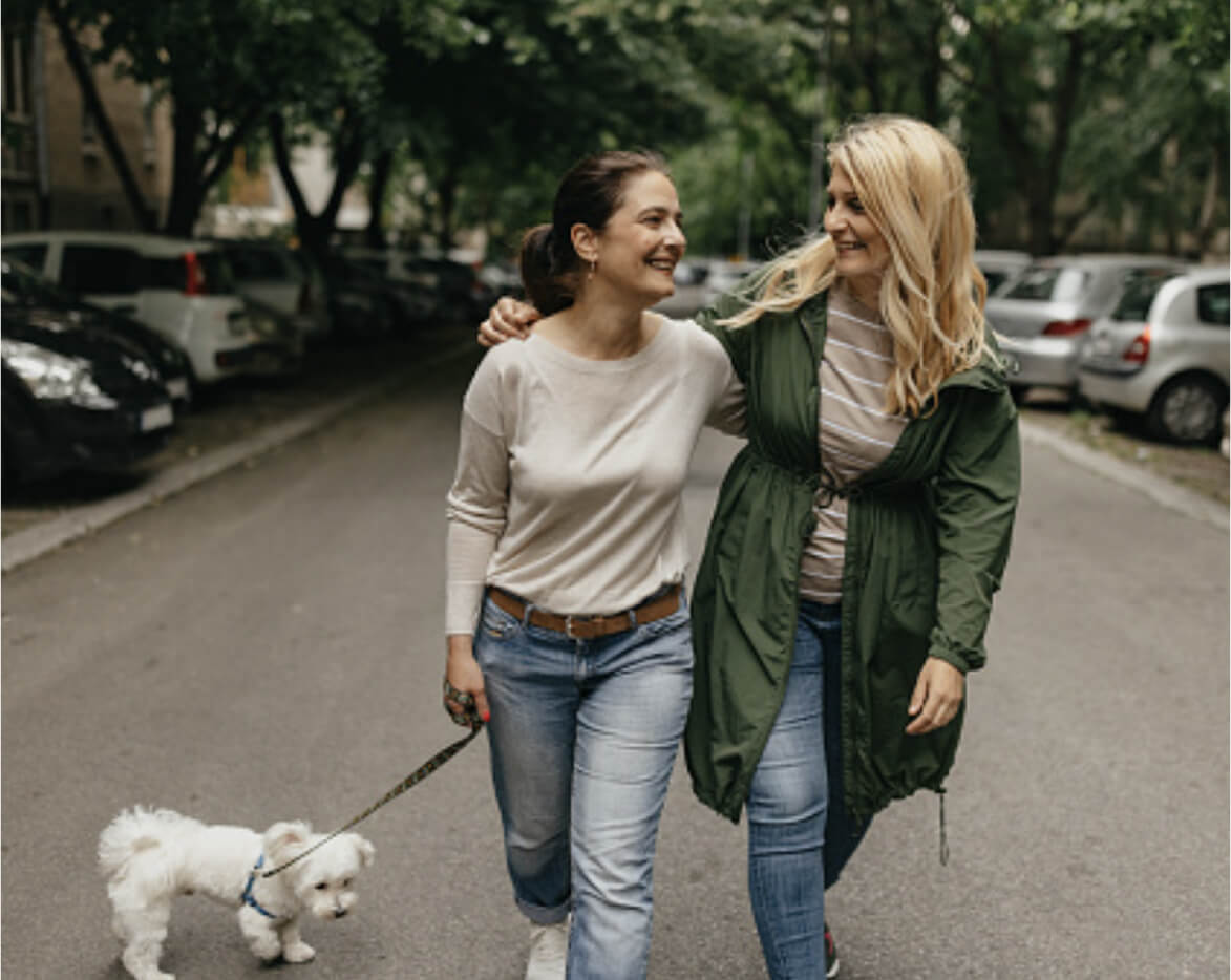 Two women walking a dog, happy after a uterine fibroid embolization procedure